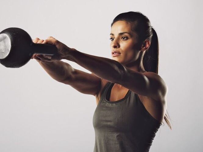 Une fille effectue un exercice avec une kettlebell pour agrandir ses seins